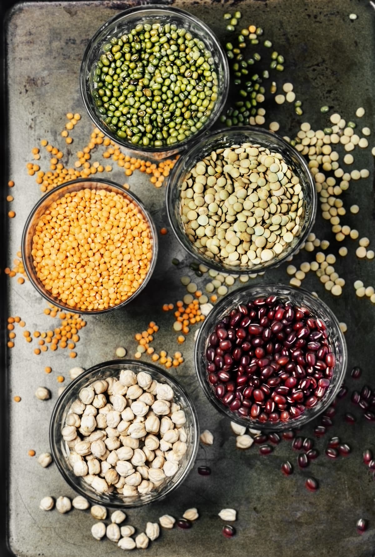 Variety of legumes in glasses on metal background