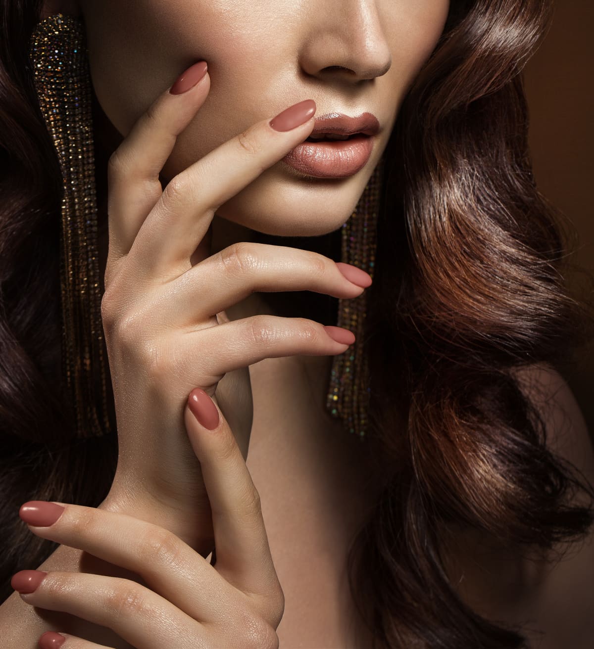 Nail manicure and nude lips make up. Women with beige nail art polish and wavy hair style close up studio portrait. Face and hand skin care cosmetics.