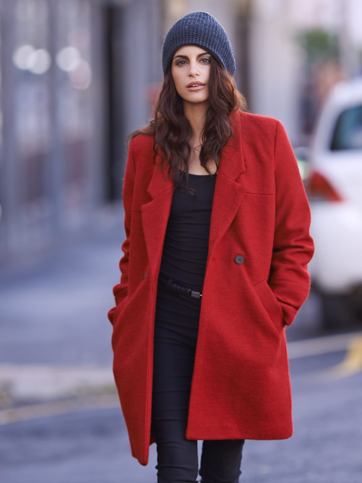 Portrait of a beautiful young woman out and about in the city wearing a red coatigan