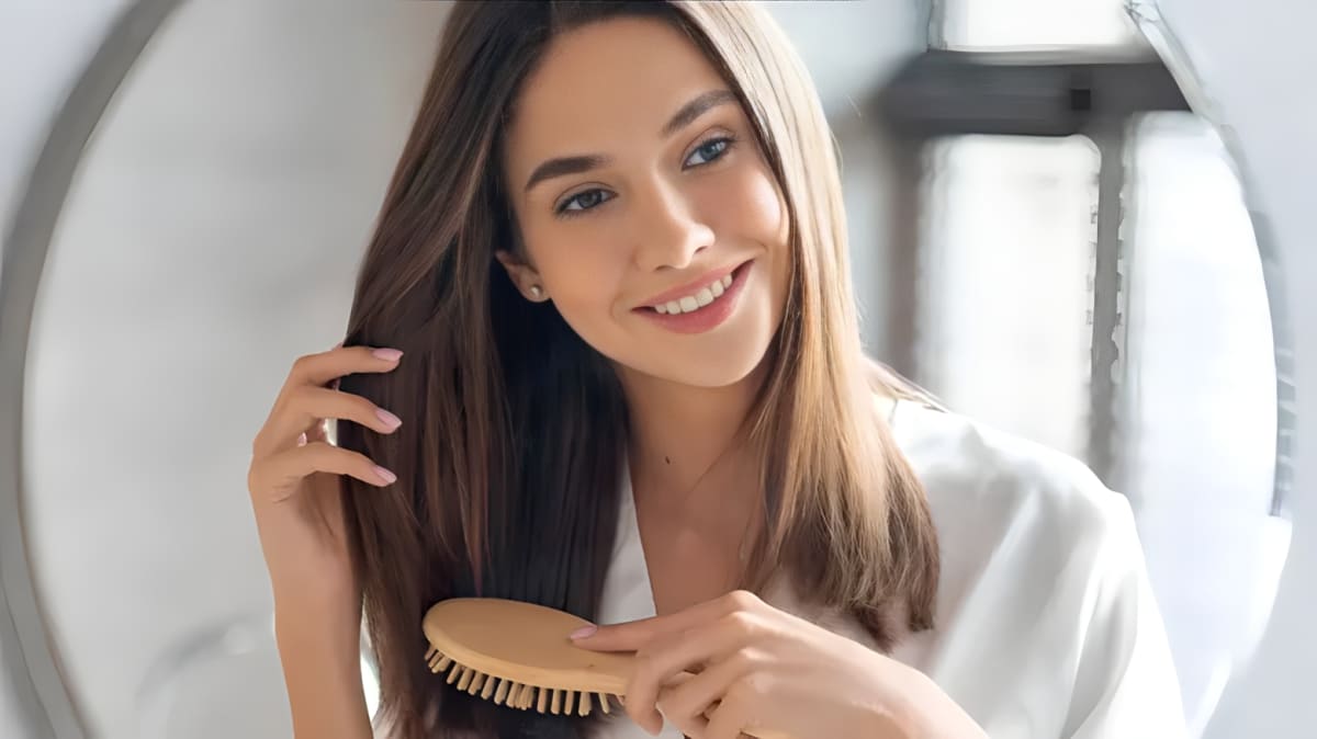 Woman smiling while combing her hair.