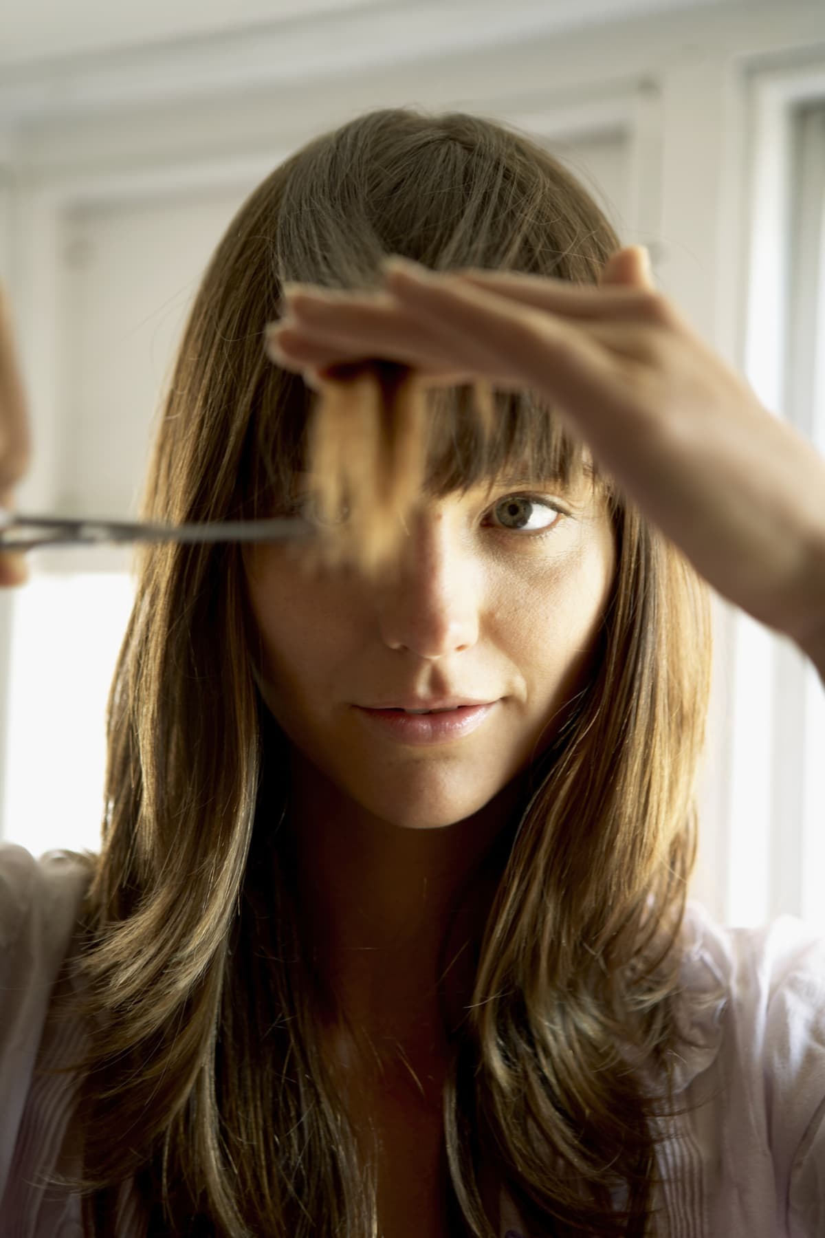 Woman cutting hair with scissors, close-up
