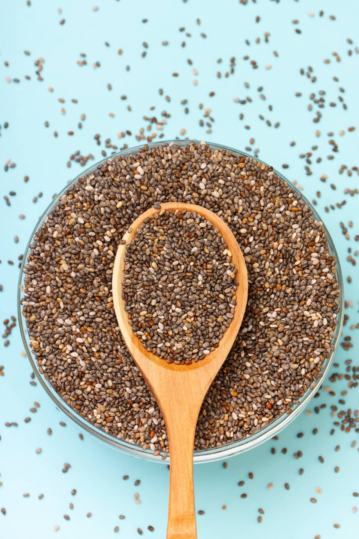 Chai seeds spread out on a dining room table, wooden spoon and white dish