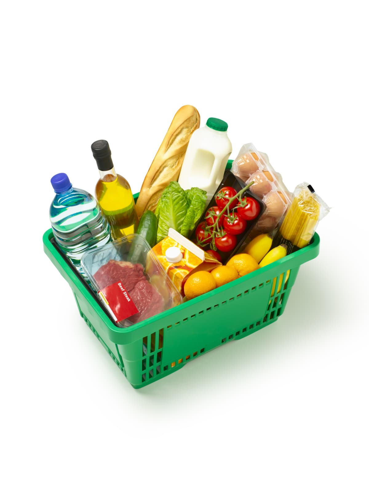 A green basket of assorted groceries against a white background