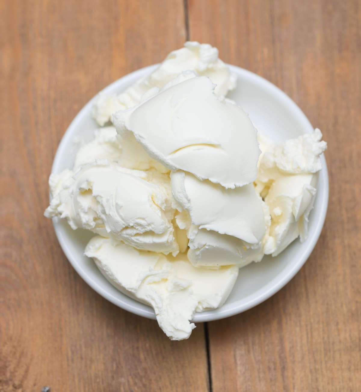 mascarpone cheese in white bowl on wooden background