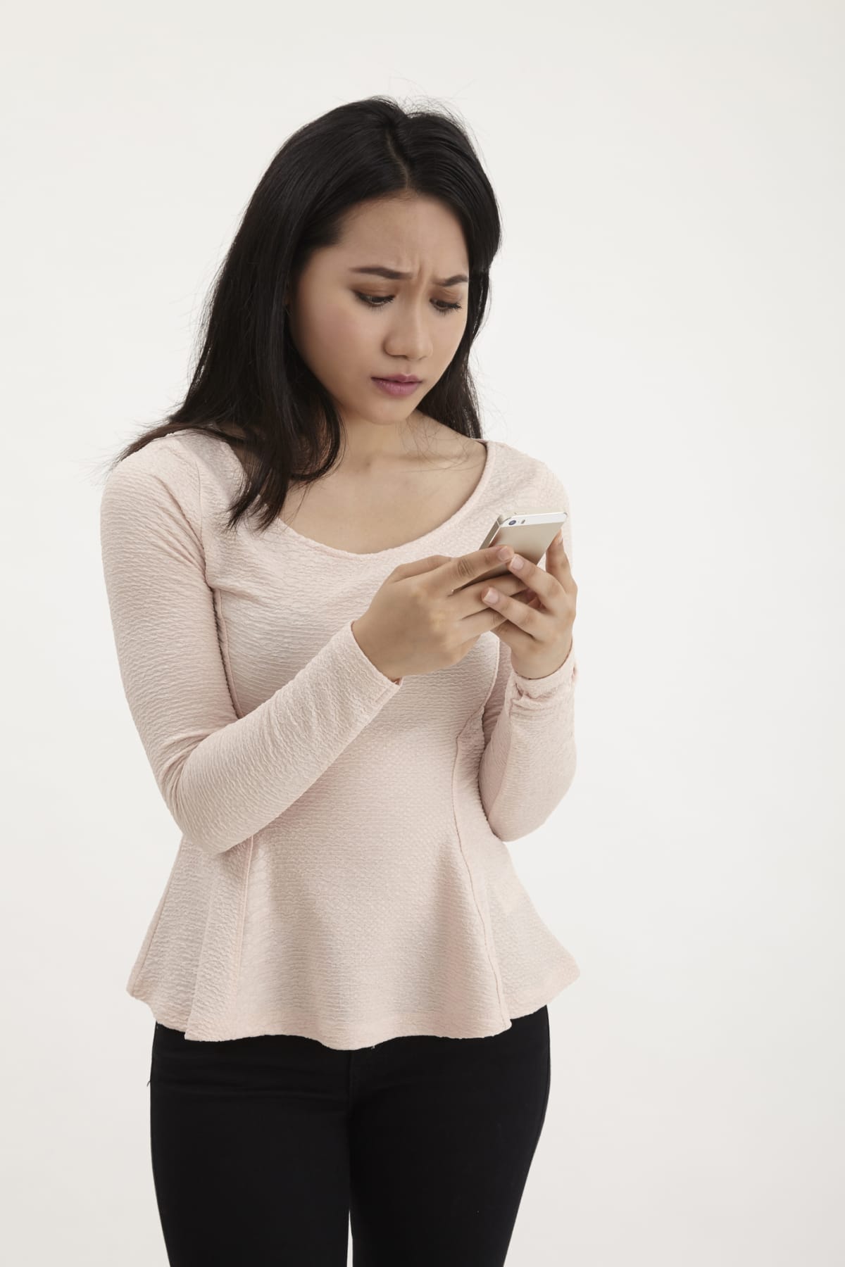 A woman looking at her phone in front of a white background