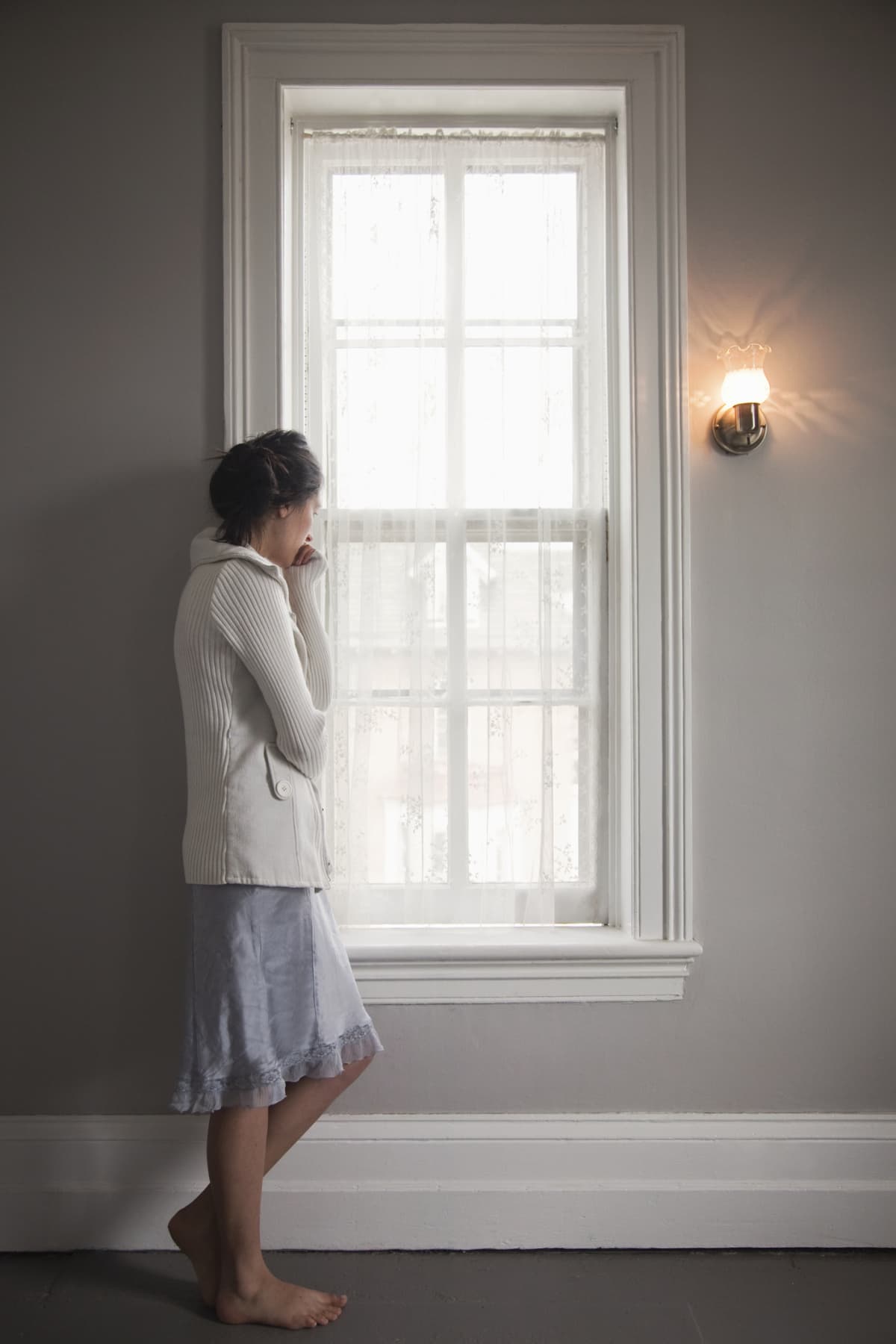 Woman standing at a window looking out.
