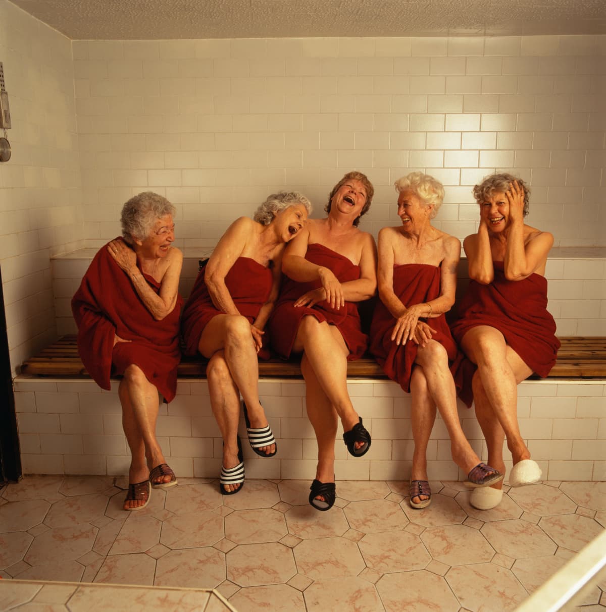 Four senior female friends laughing in a steam room 