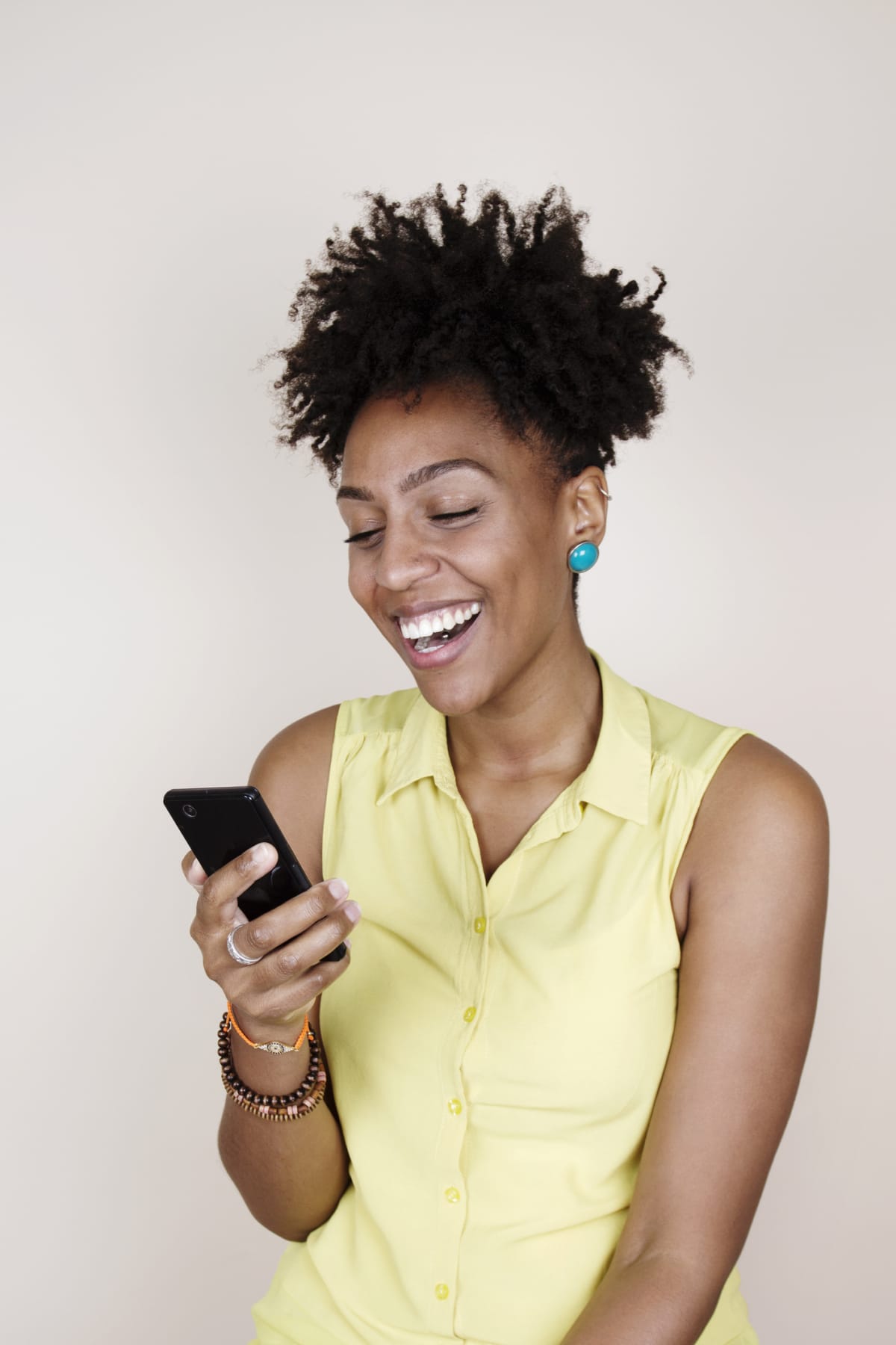 Woman smiling widely while looking at her smartphone