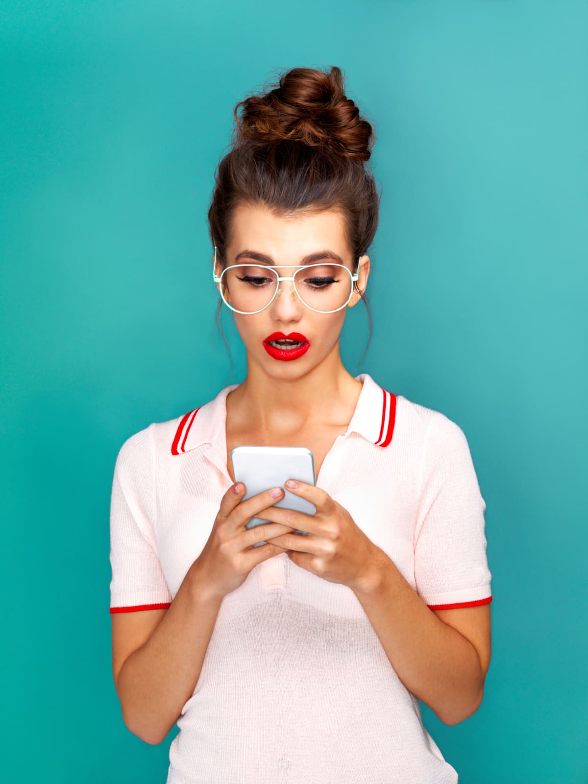Young woman looks down at her smartphone with a shocked expression