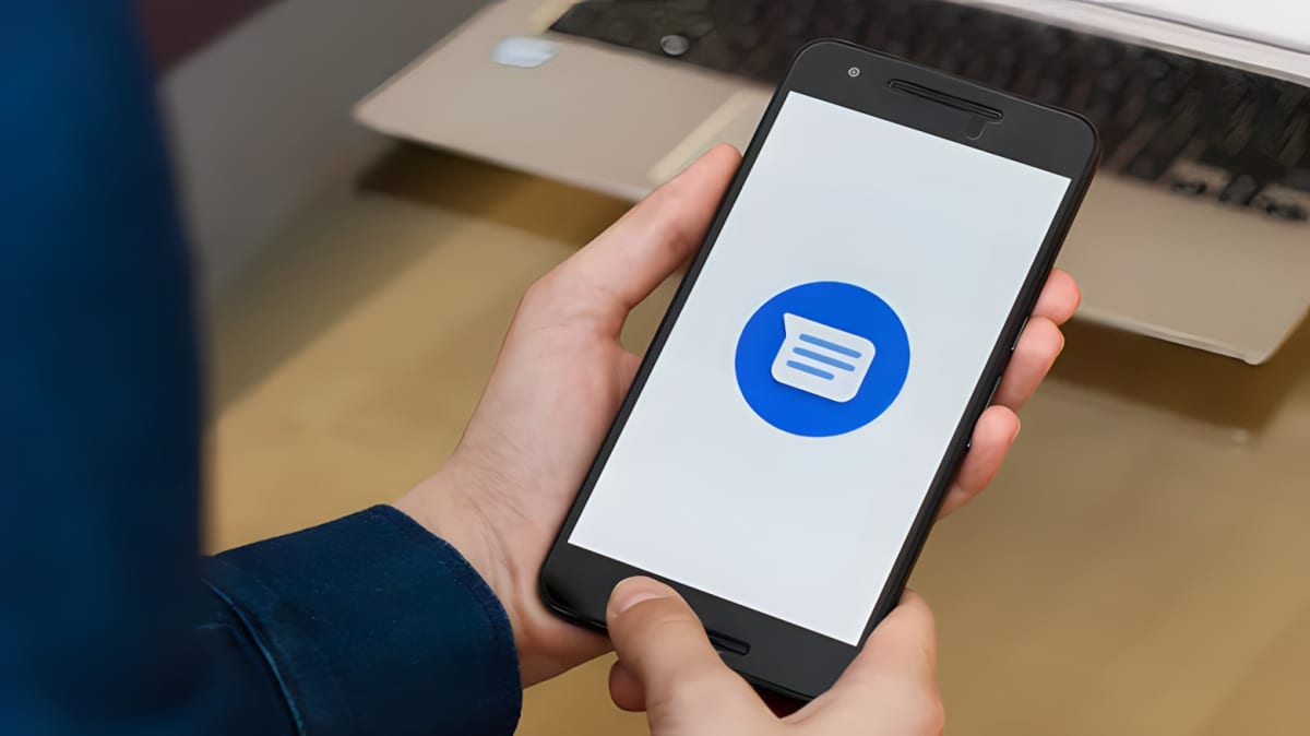 Hand holding an android phone displaying the messaging app icon