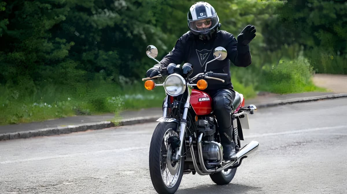 Motorcyclist waving while riding a Kawasaki motorcycle