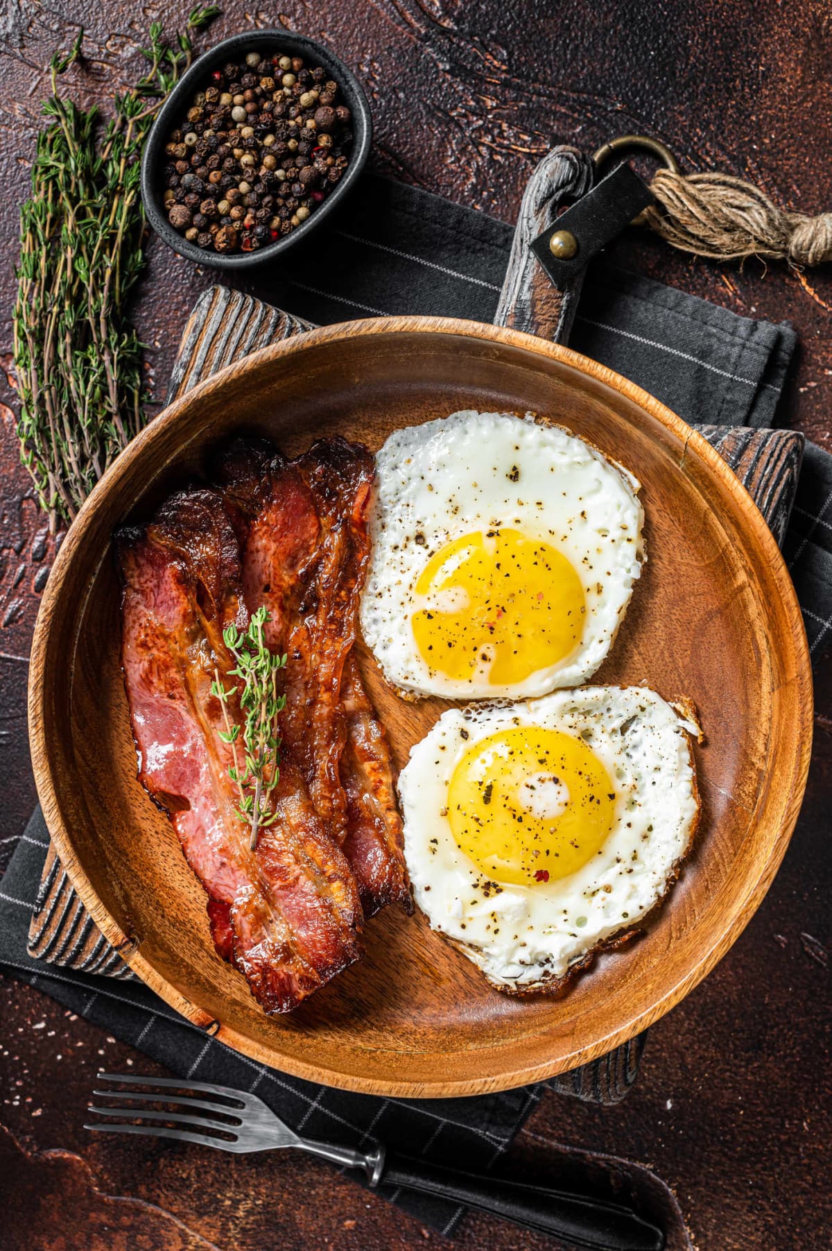 Fried eggs and bacon on a wooden plate