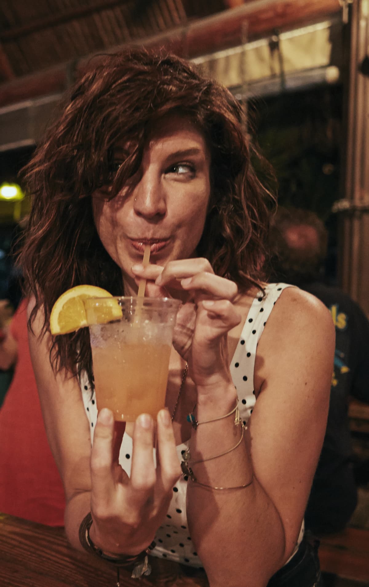 A young woman sips a mocktail while smiling