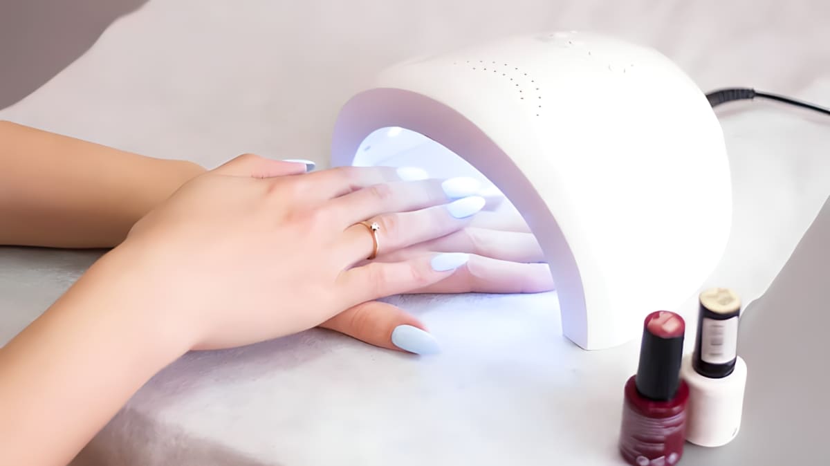 Hands with a gel manicure under the dryer's UV light