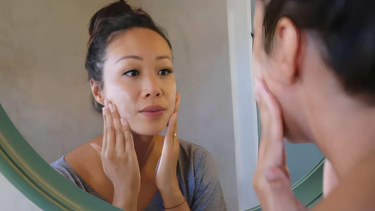 A woman uses skin cream on her face