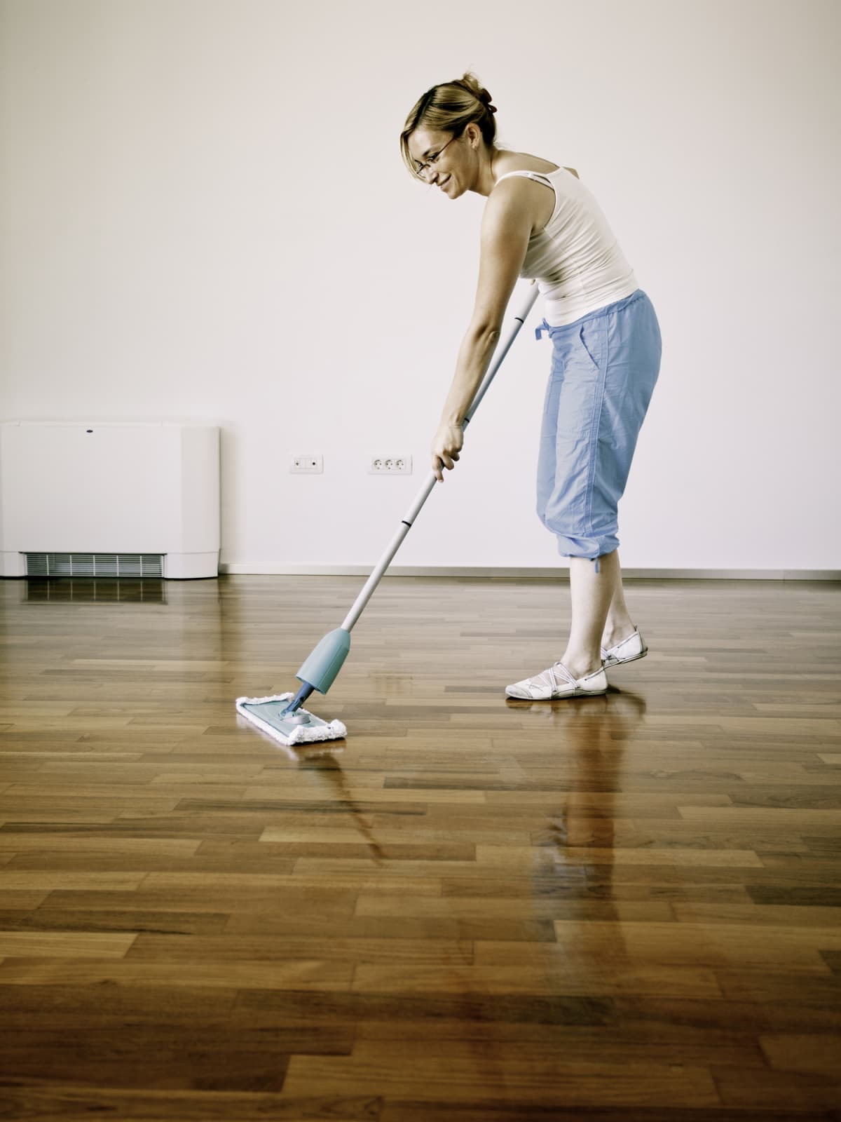 Young woman cleaning wooden floor.