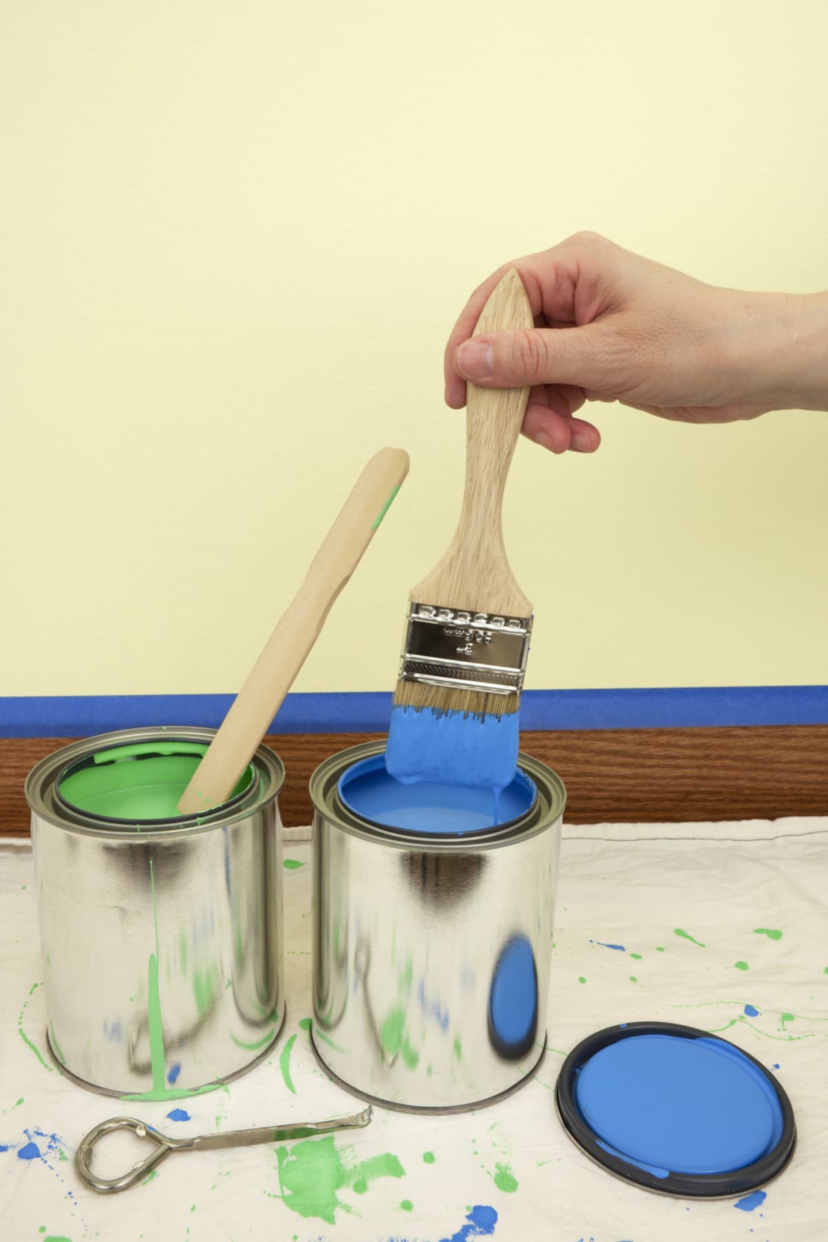 A person dipping paint brush in a can of paint