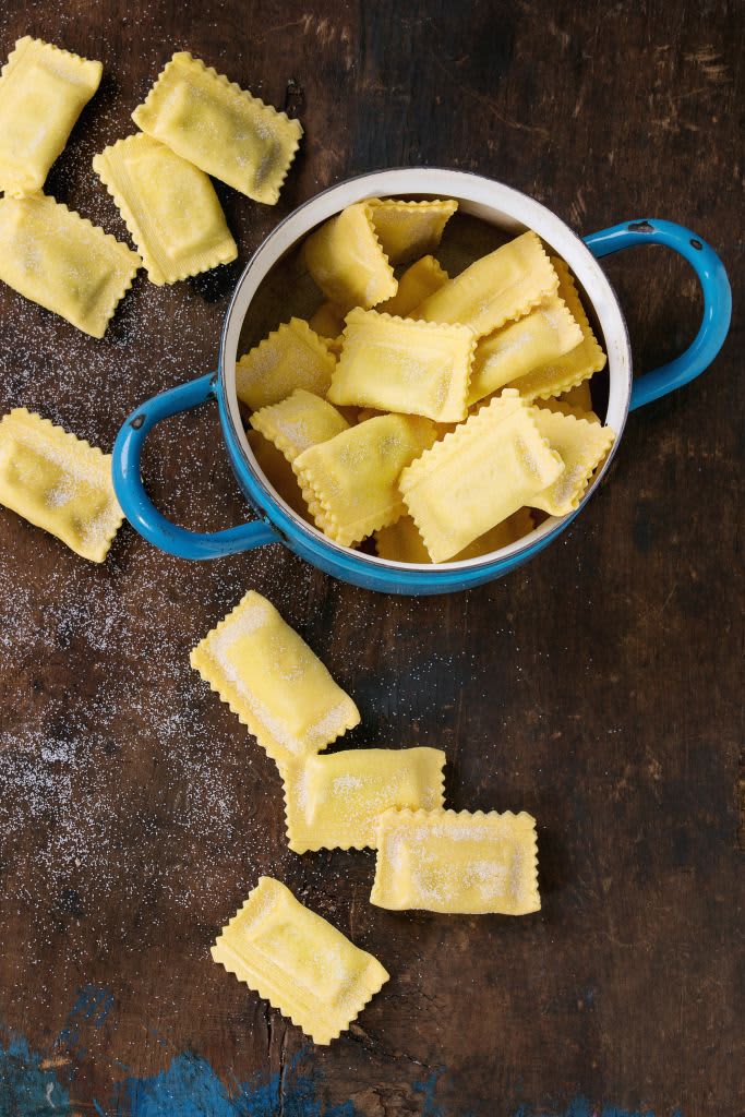 Fresh maked raw uncooked italian pasta ravioli in vintage blue pan over old dark wooden background. Top view with copy space. (Photo by: Natasha Breen/REDA&CO/Universal Images Group via Getty Images)