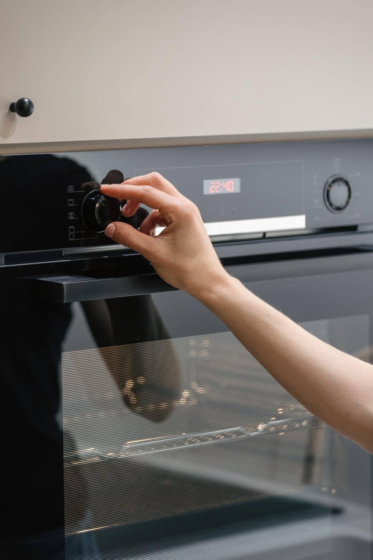 Woman turn setting button on new built-in electric oven, choosing temperature for cooking and select time for baking food. Female using microwave with defrosting and grilling mode