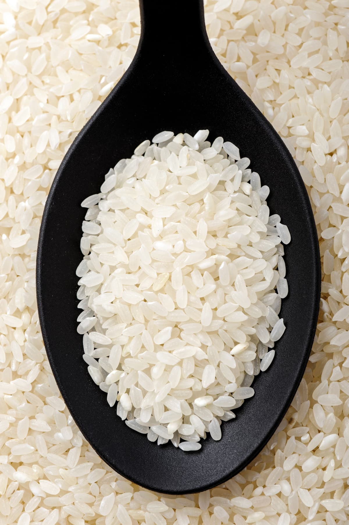 Top view of black spoon full of calrose rice