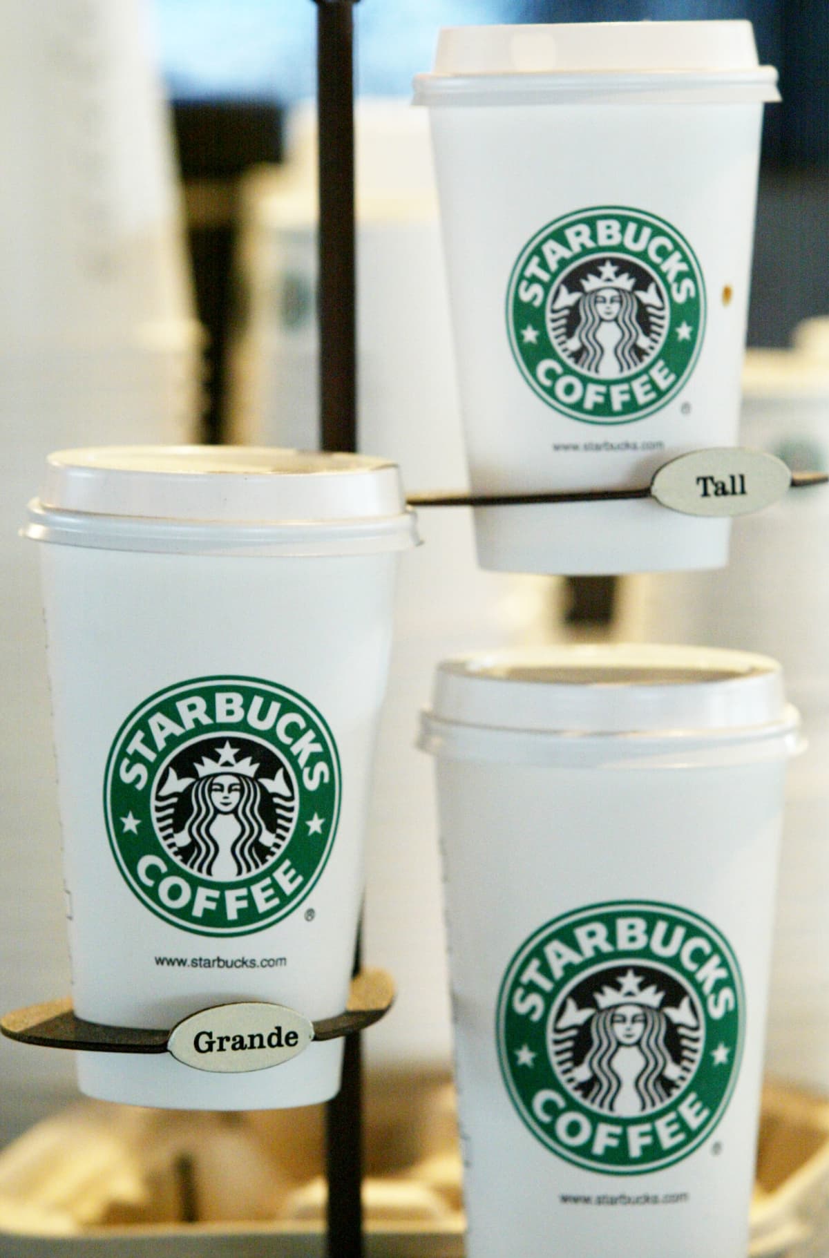 A paper Starbucks cup in front of a Starbucks store.