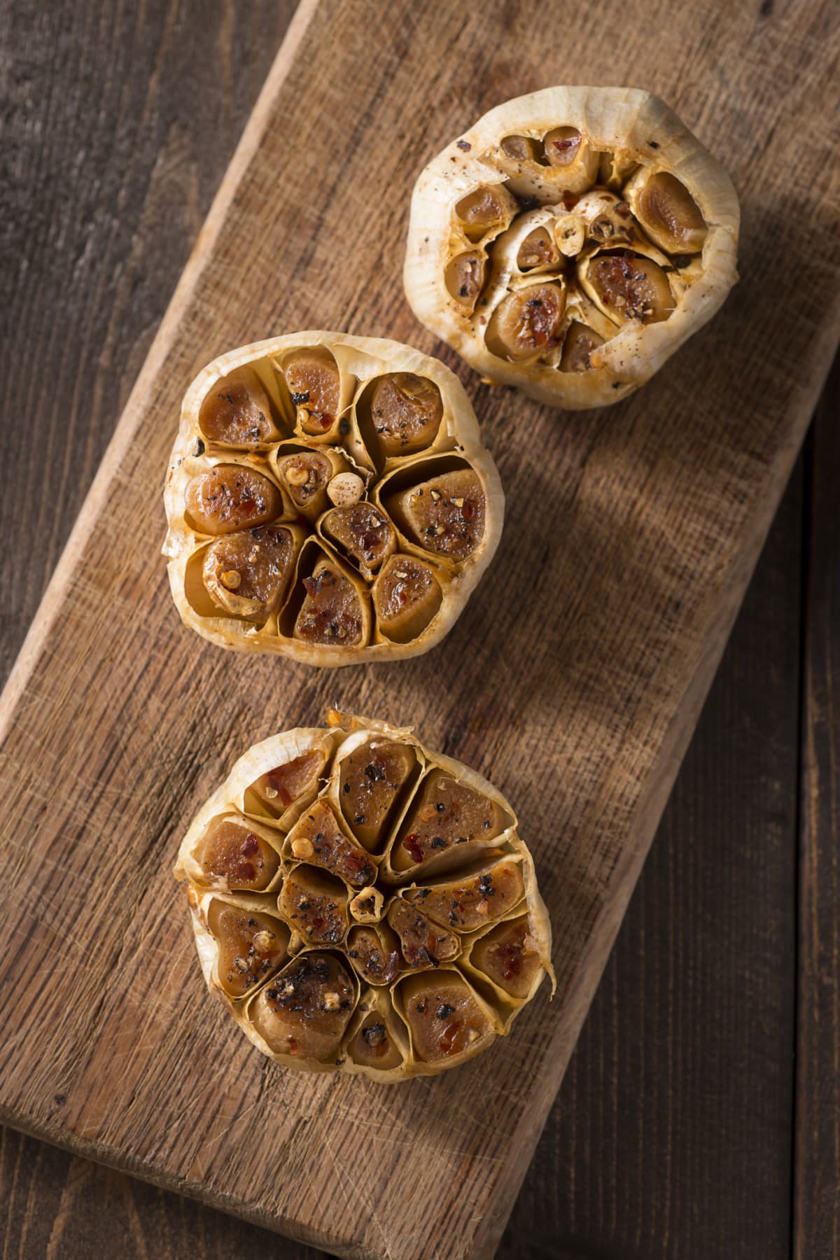 Roasted garlic bulbs on a wooden serving board