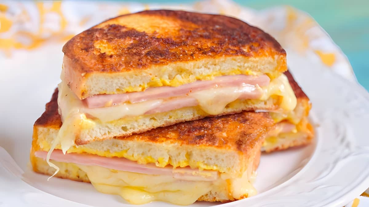 A monte cristo sandwich with melted cheese, mustard, meat, and mayonnaise