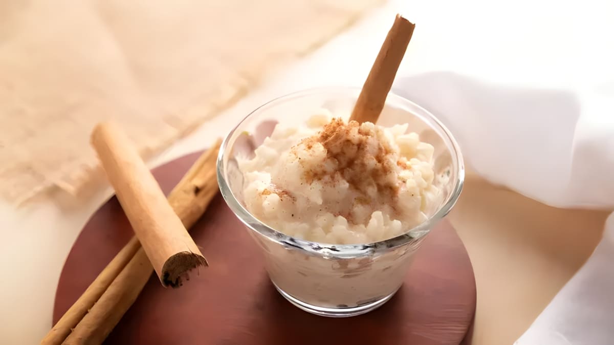 Rice pudding in a clear bowl with a cinnamon stick