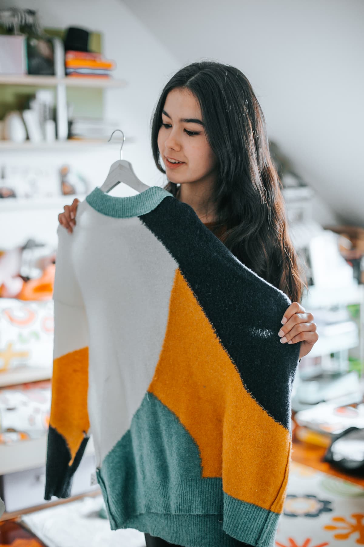 young woman choosing a sweater from her closet