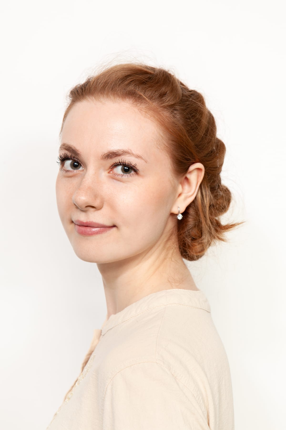 Close-up studio portrait of an attractive 24 year old red-haired woman in a beige blouse on a white background