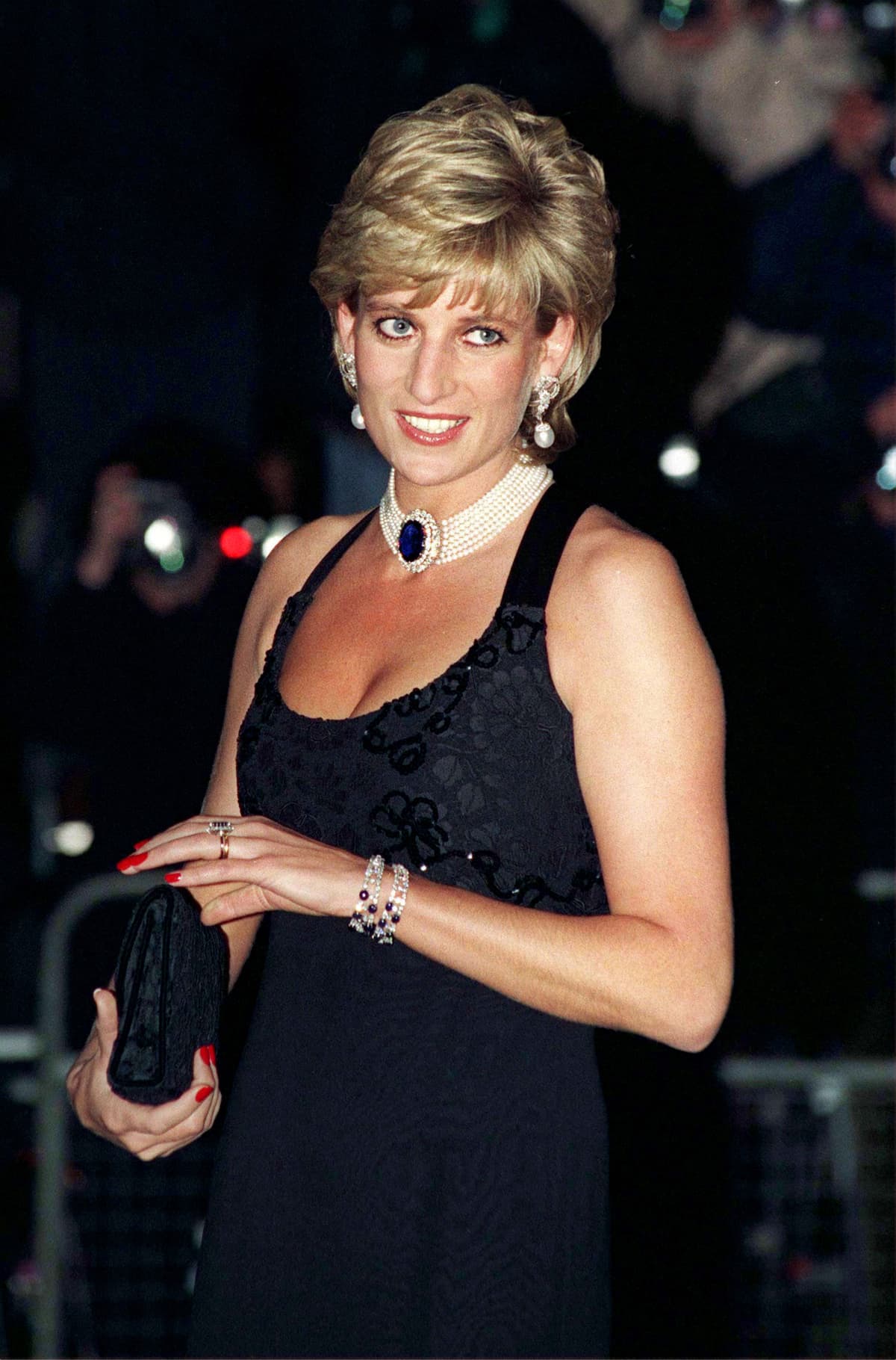 Diana, Princess Of Wales, smiling in a black sleeveless dress.