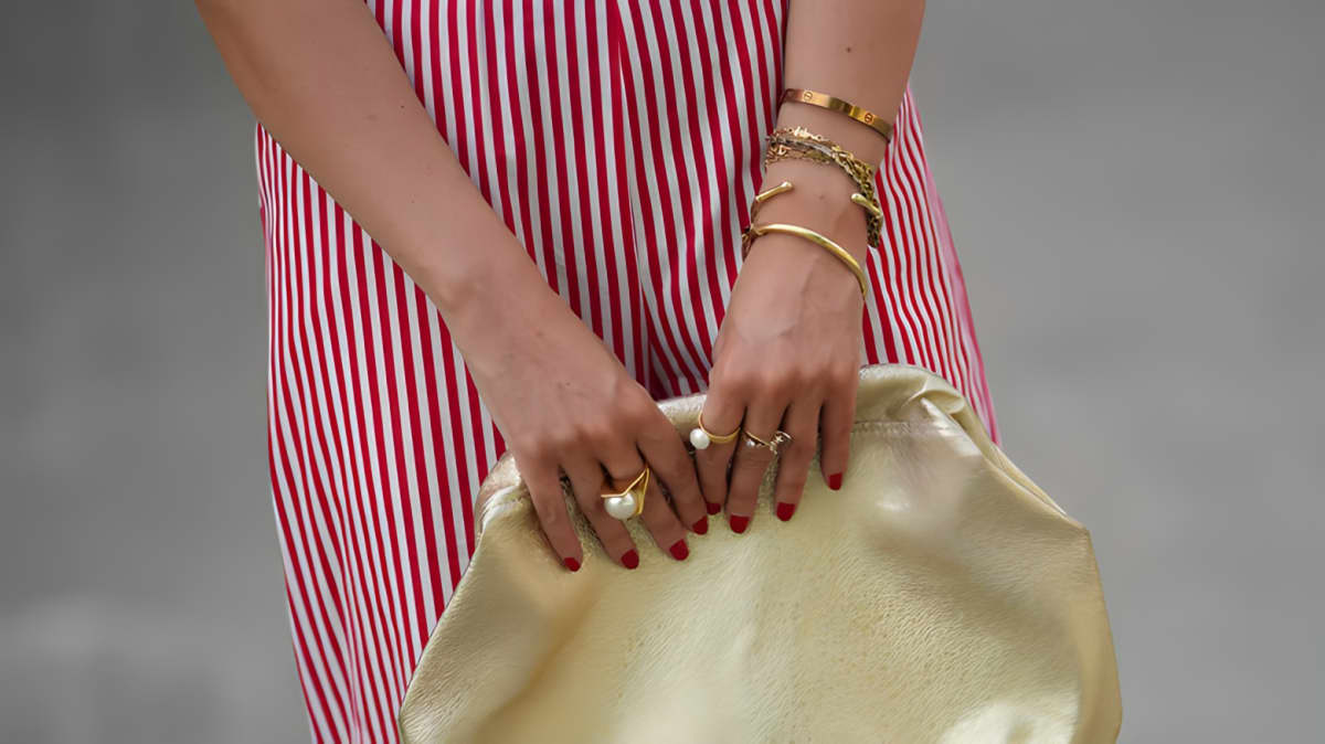 A woman in a white and red striped dress with a stack of bracelets on her wrist