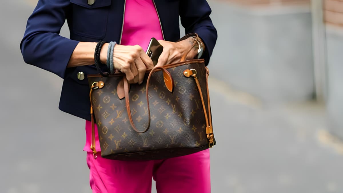 Woman reaching into her Louis Vuitton Neverfull tote.