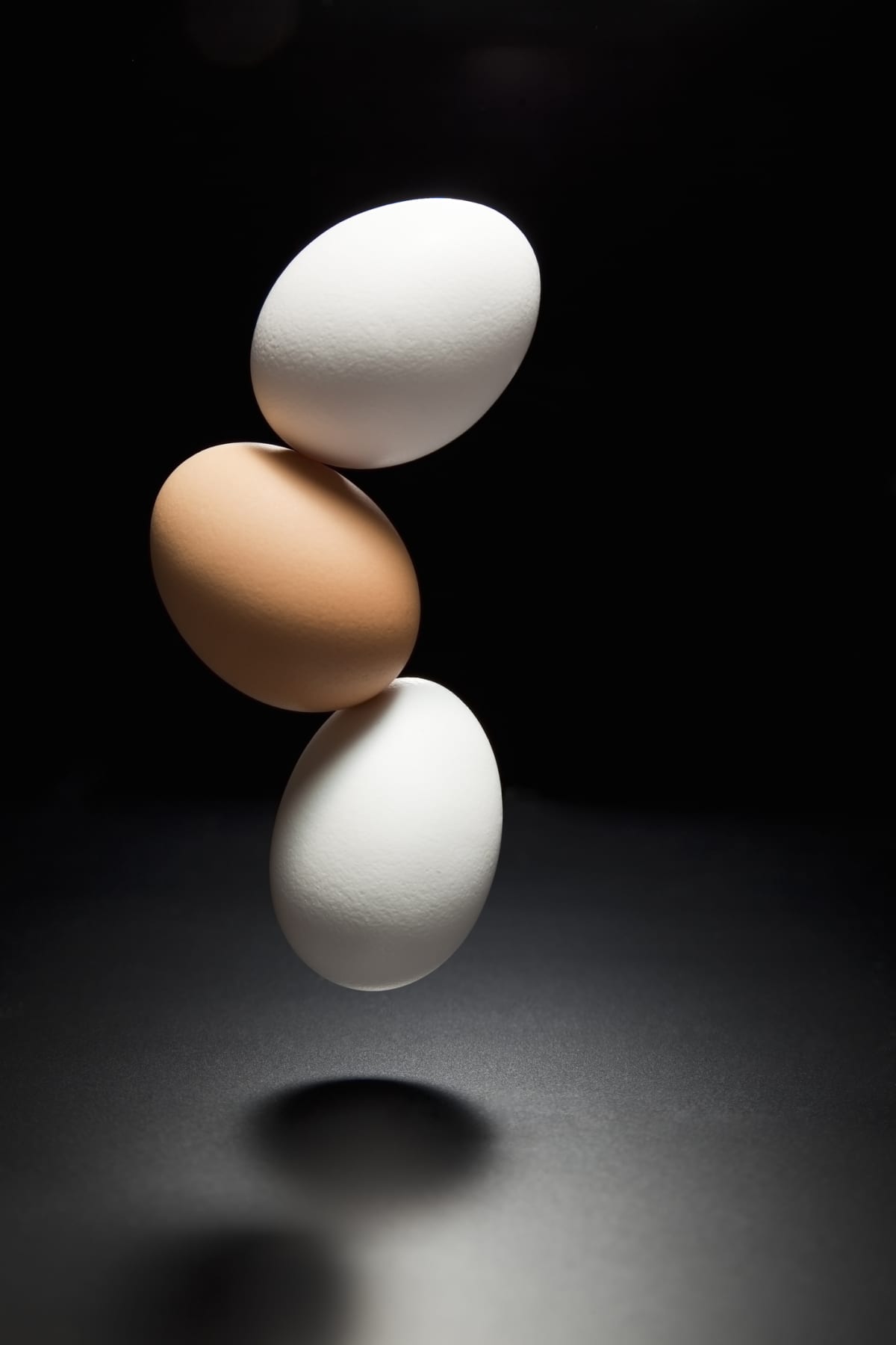 Three eggs falling on a black background