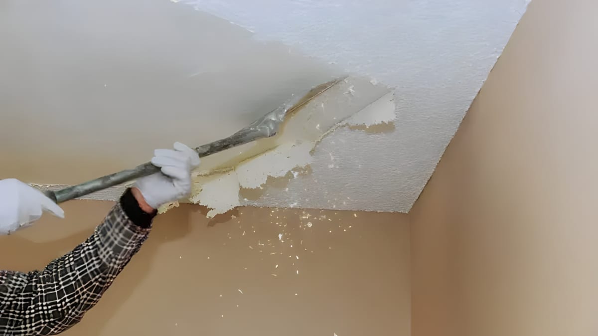 A person scraping popcorn ceiling