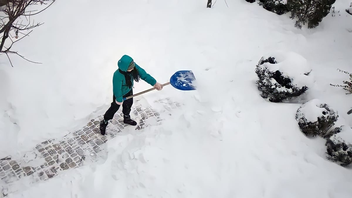 A person clearing snow off driveway with a shovel