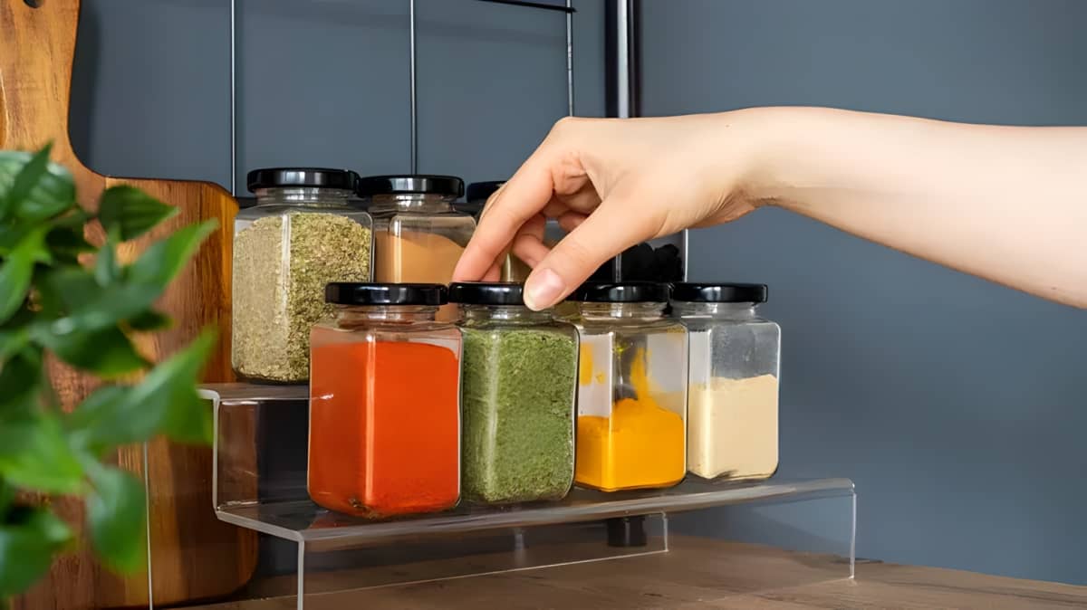 A person taking out spice from kitchen rack