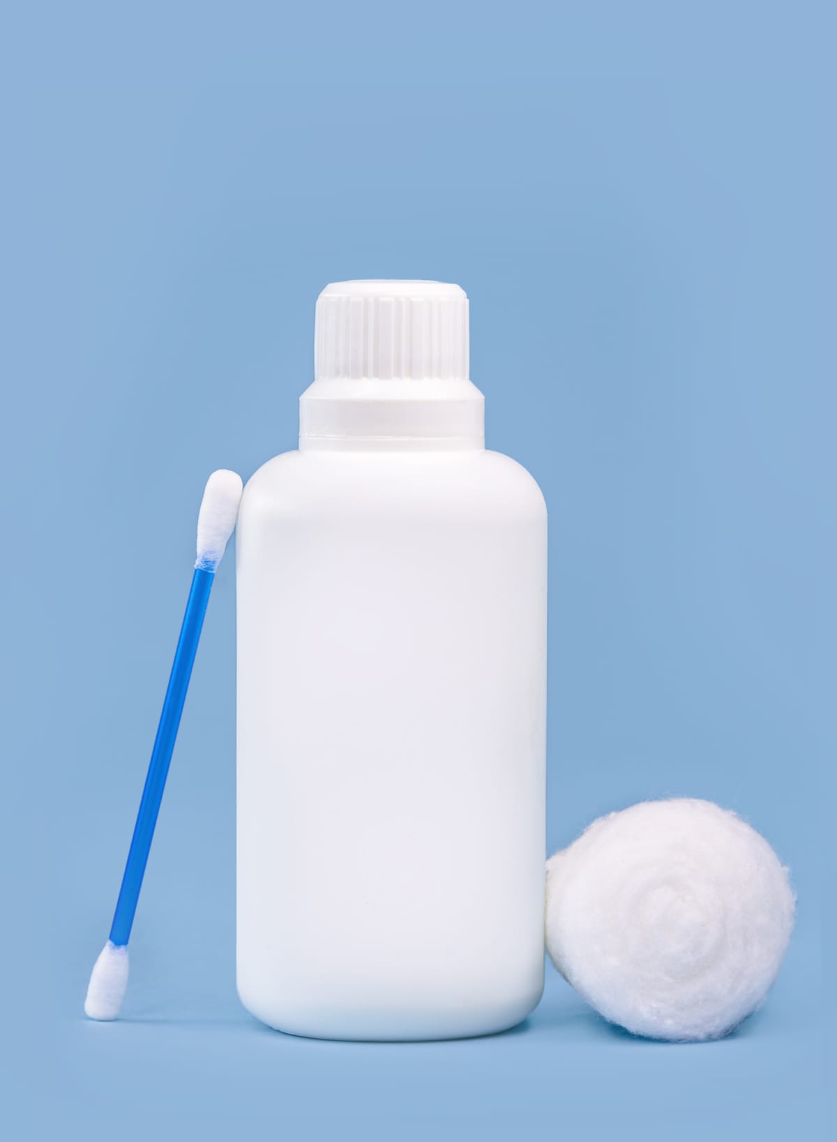 Hydrogen Peroxide next to cotton swab and cotton ball, blue background