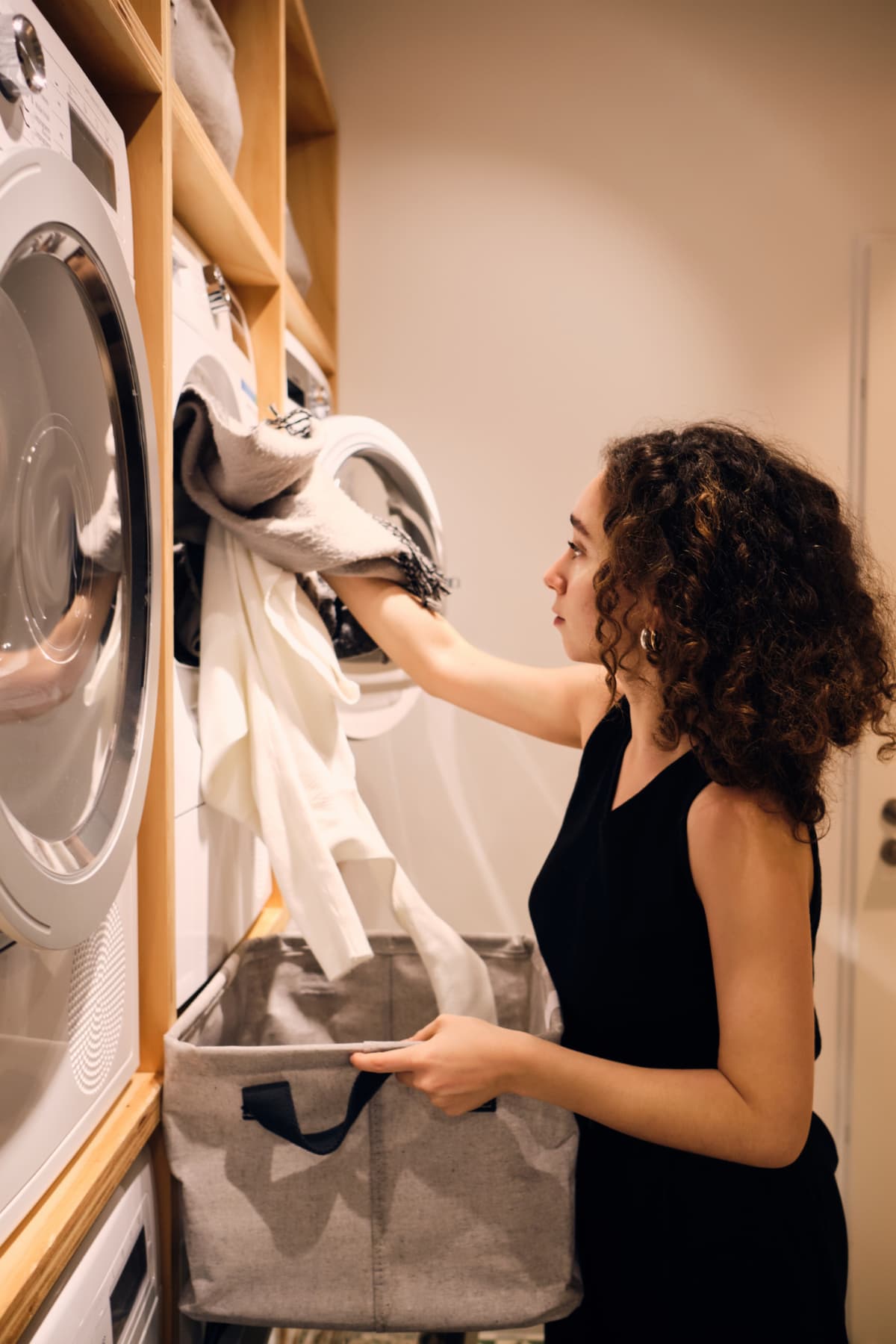 woman loading laundry into stacked front loading washing machine