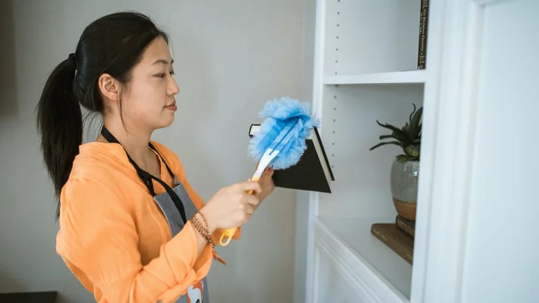 A woman dusting a book with a Swiffer