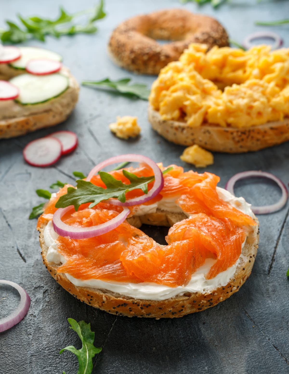 bagels with salmon, scrambled eggs, vegetables and cream cheese.