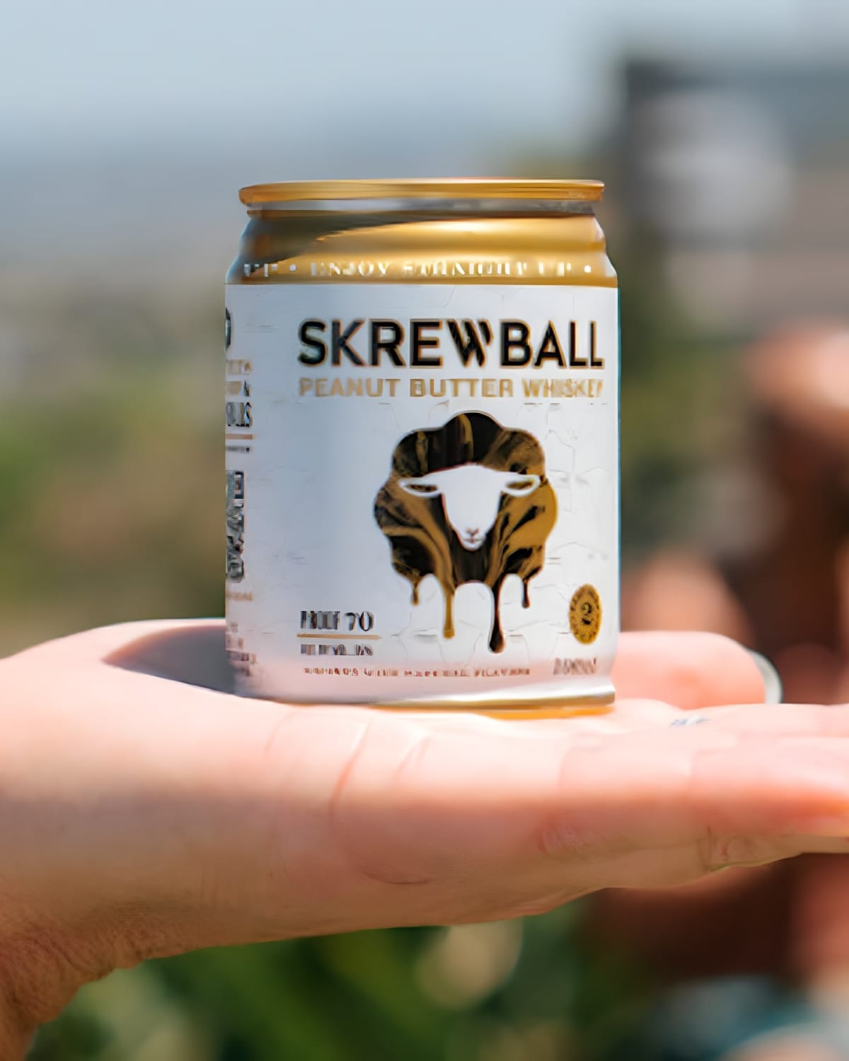 Hand holding a can of Skrewball's peanut butter whiskey