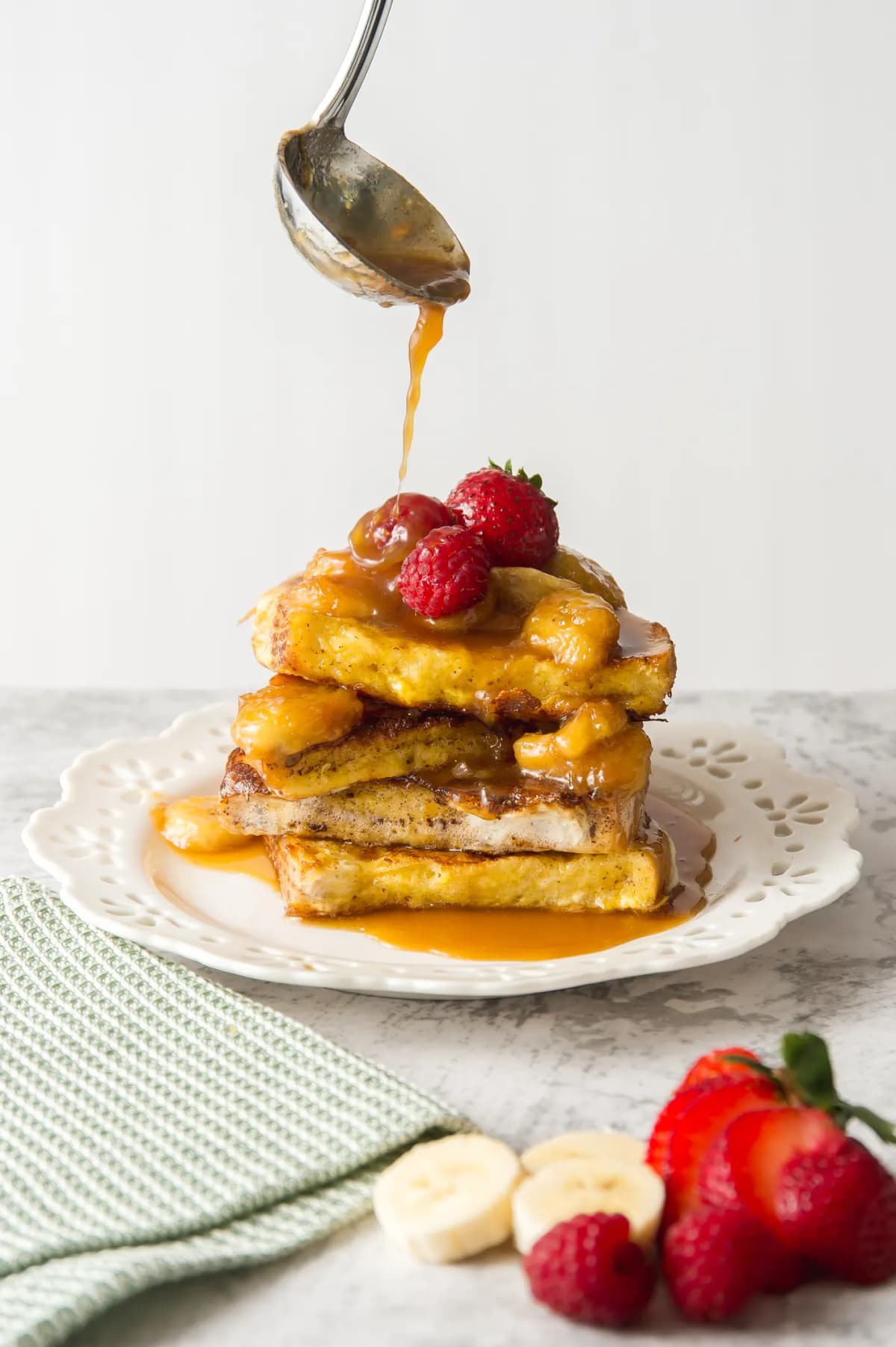 Caramel being poured on French toast with fruits
