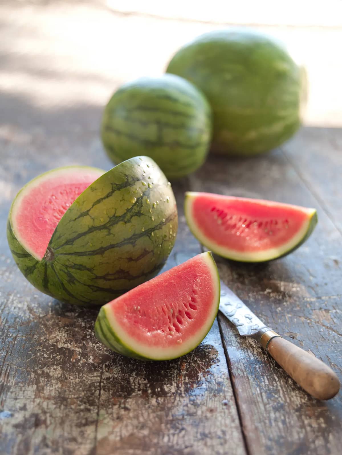 Whole and cut watermelons next to knife