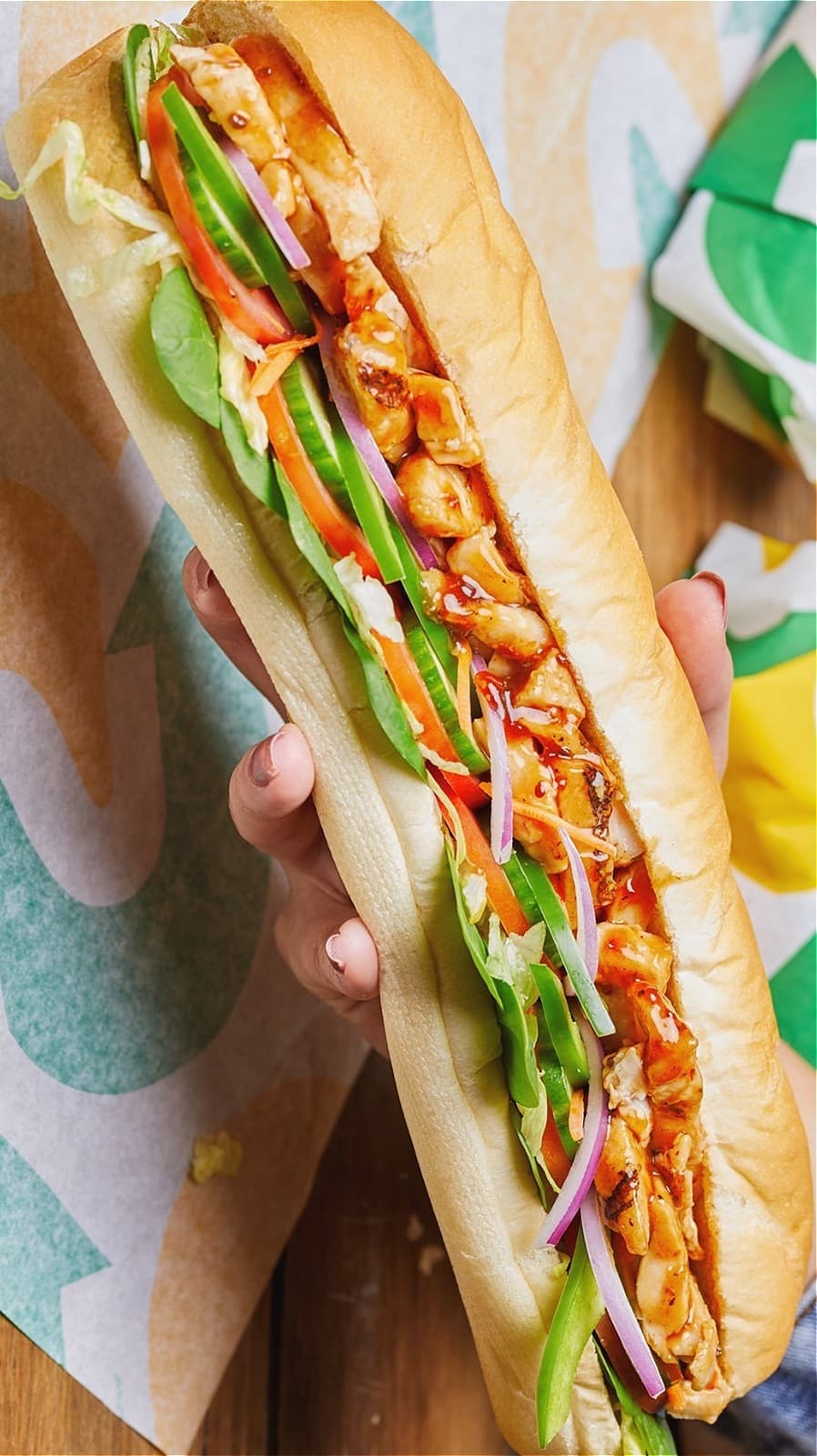 Hand holding a Subway sandwich