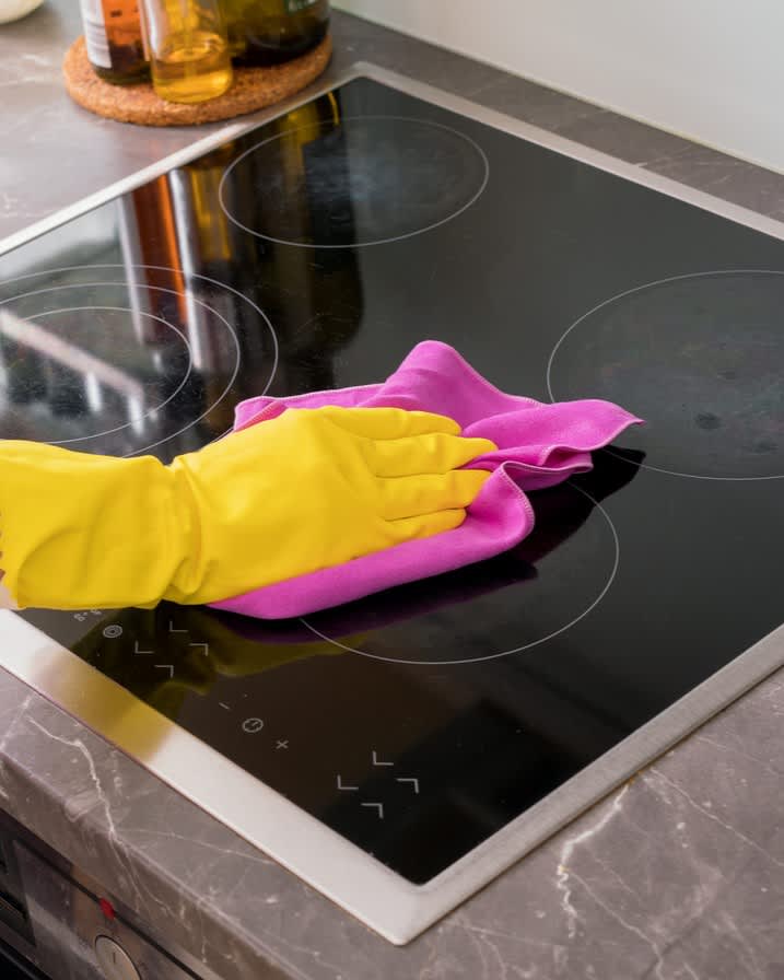 Gloved hand cleaning glass-top stove