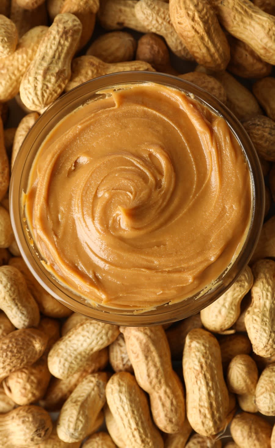 Bowl of peanut butter on top of a pile of peanuts