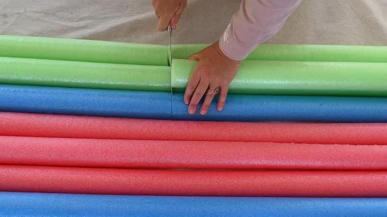 Person cutting row of pool noodles