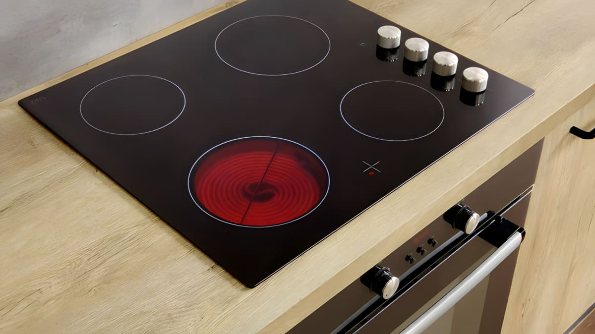 Glass cooktop with one burner lit.