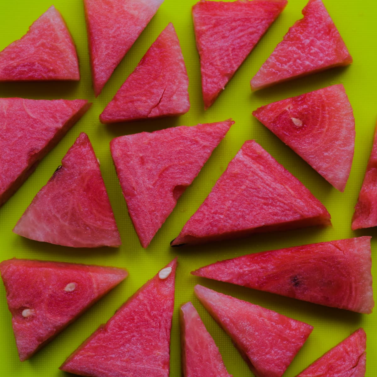 A square cropped image of variously shaped slices of fresh, vibrant watermelon